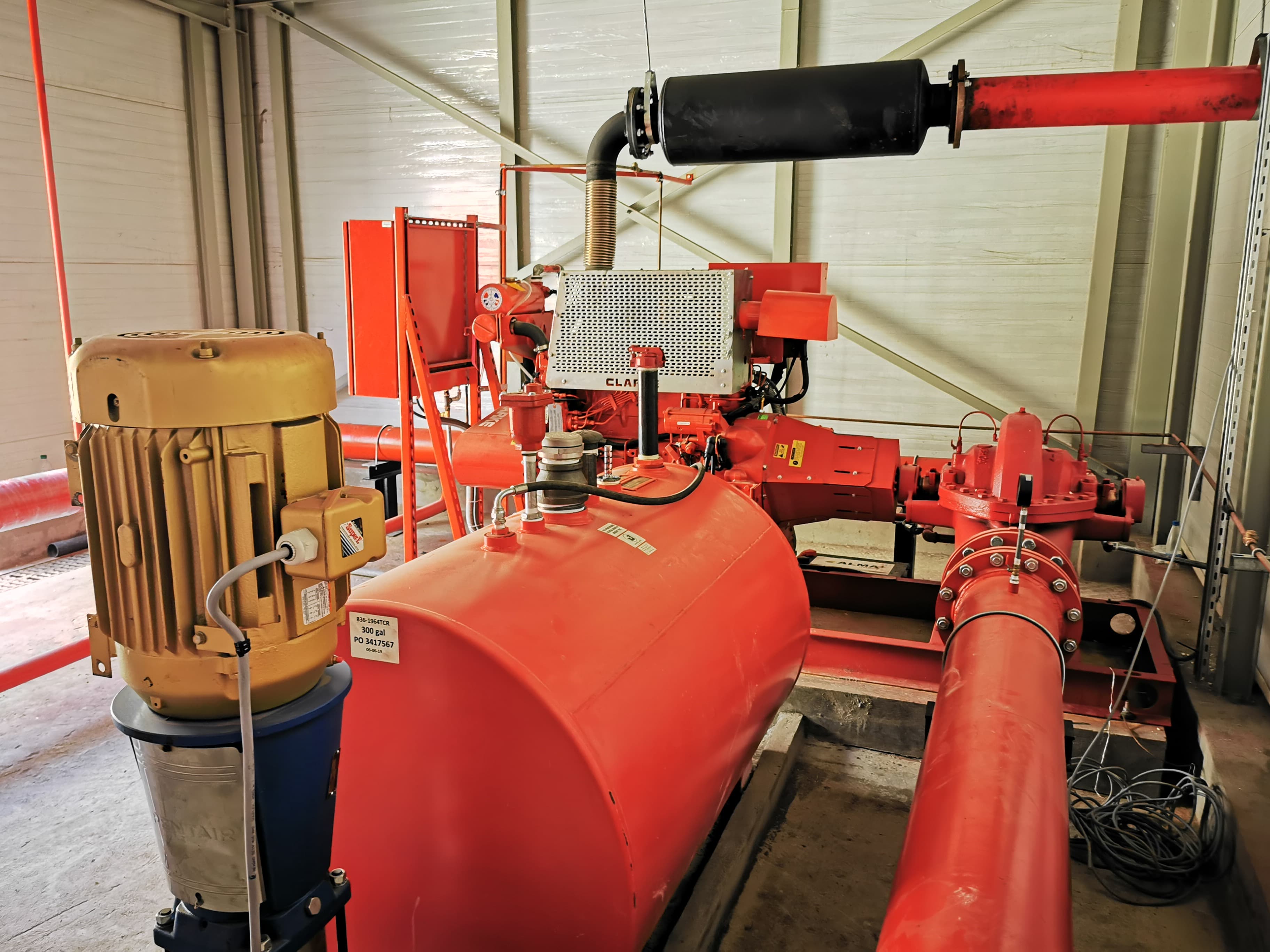 Système de pompe à incendie avec réservoir rouge, moteur jaune et tuyauterie rouge.